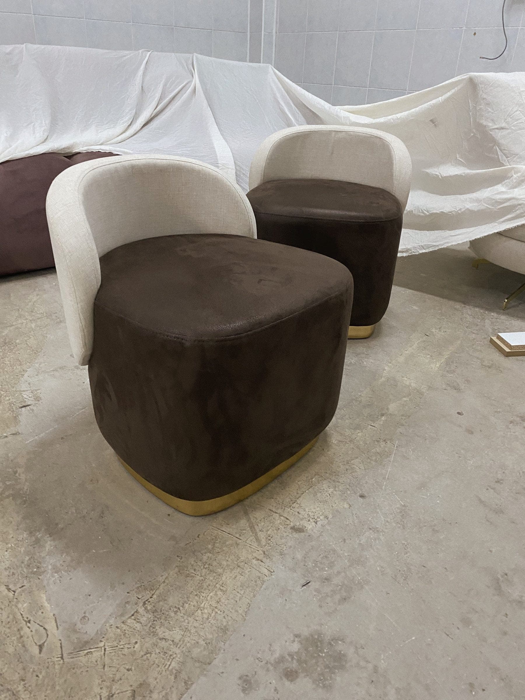 Fertige Bouclé-Sessel und Hocker unter Staubschutz im Werk.