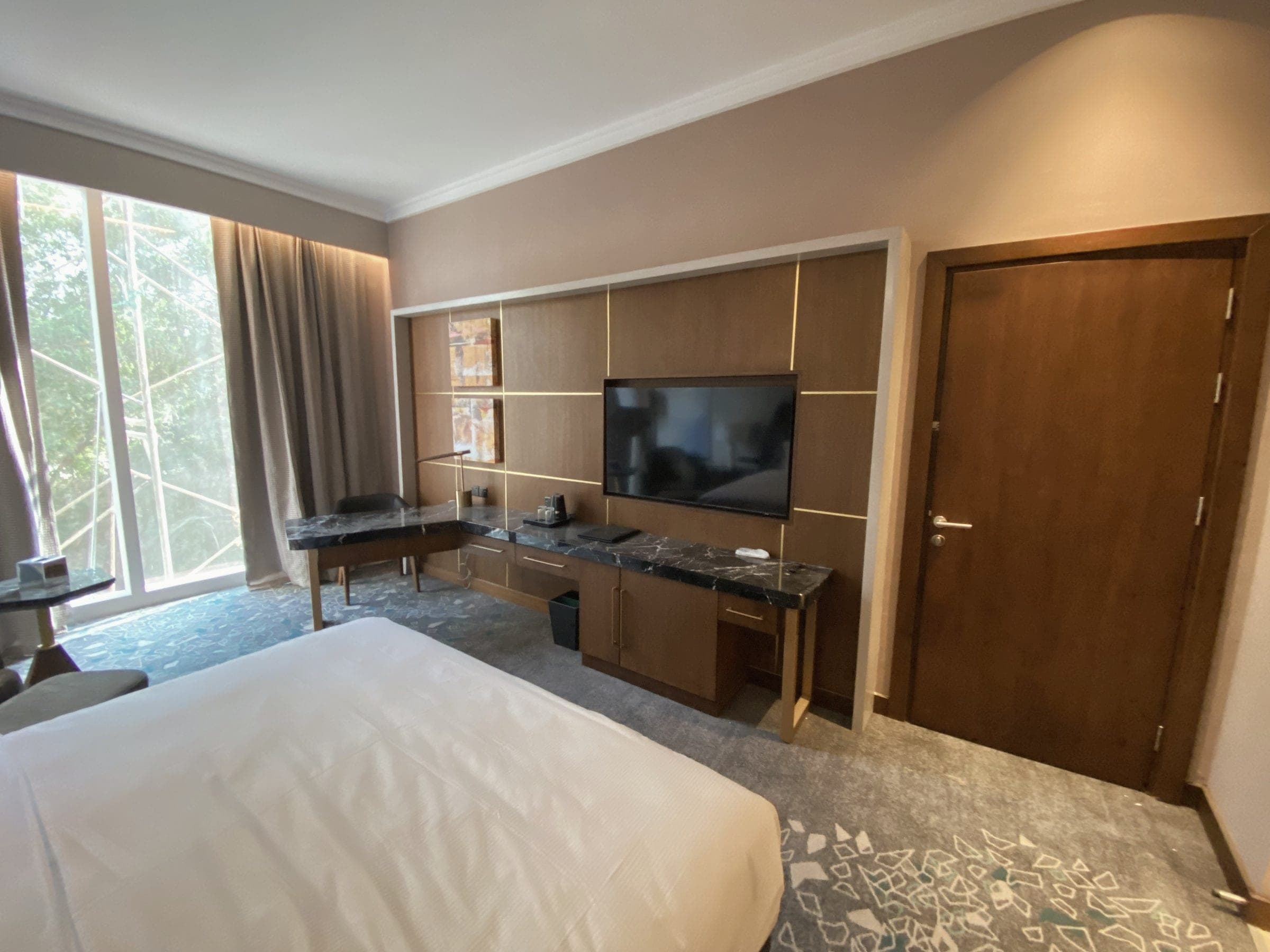 Schreibtisch und TV-Element im Gästezimmer, dahinter Eingangstür und Schrank.