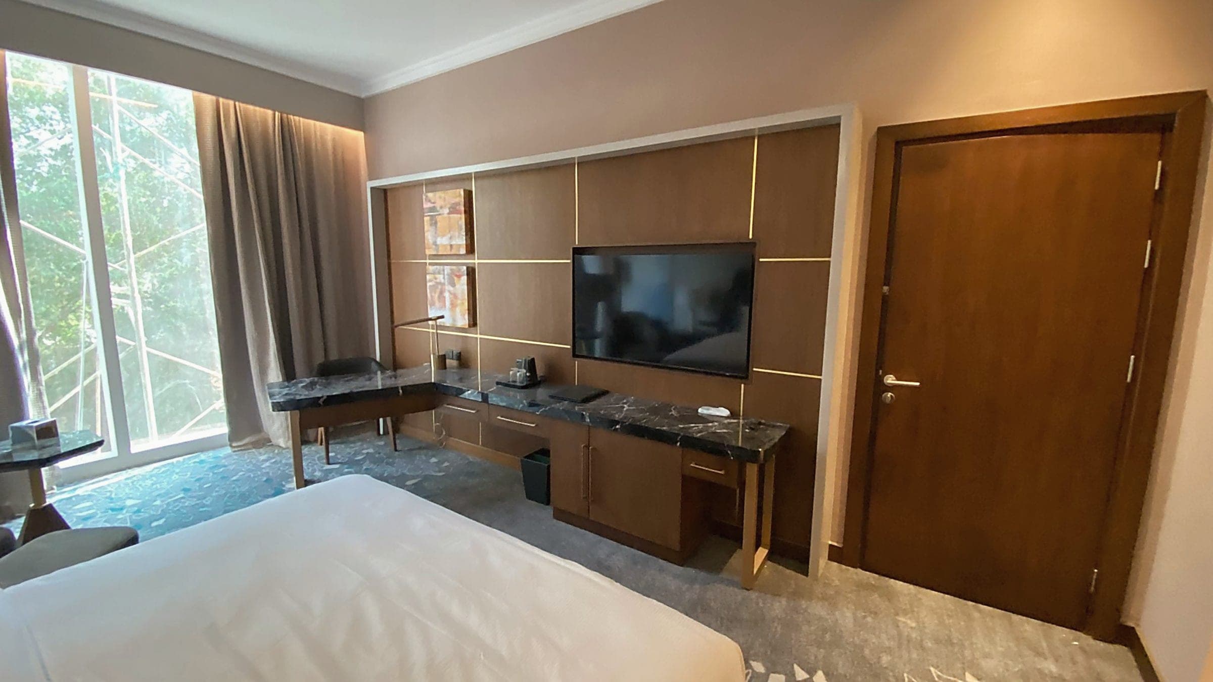 Gästezimmer vom Bett aus: Schreibtisch, TV-Element, Eingangstür und Fensterwand.