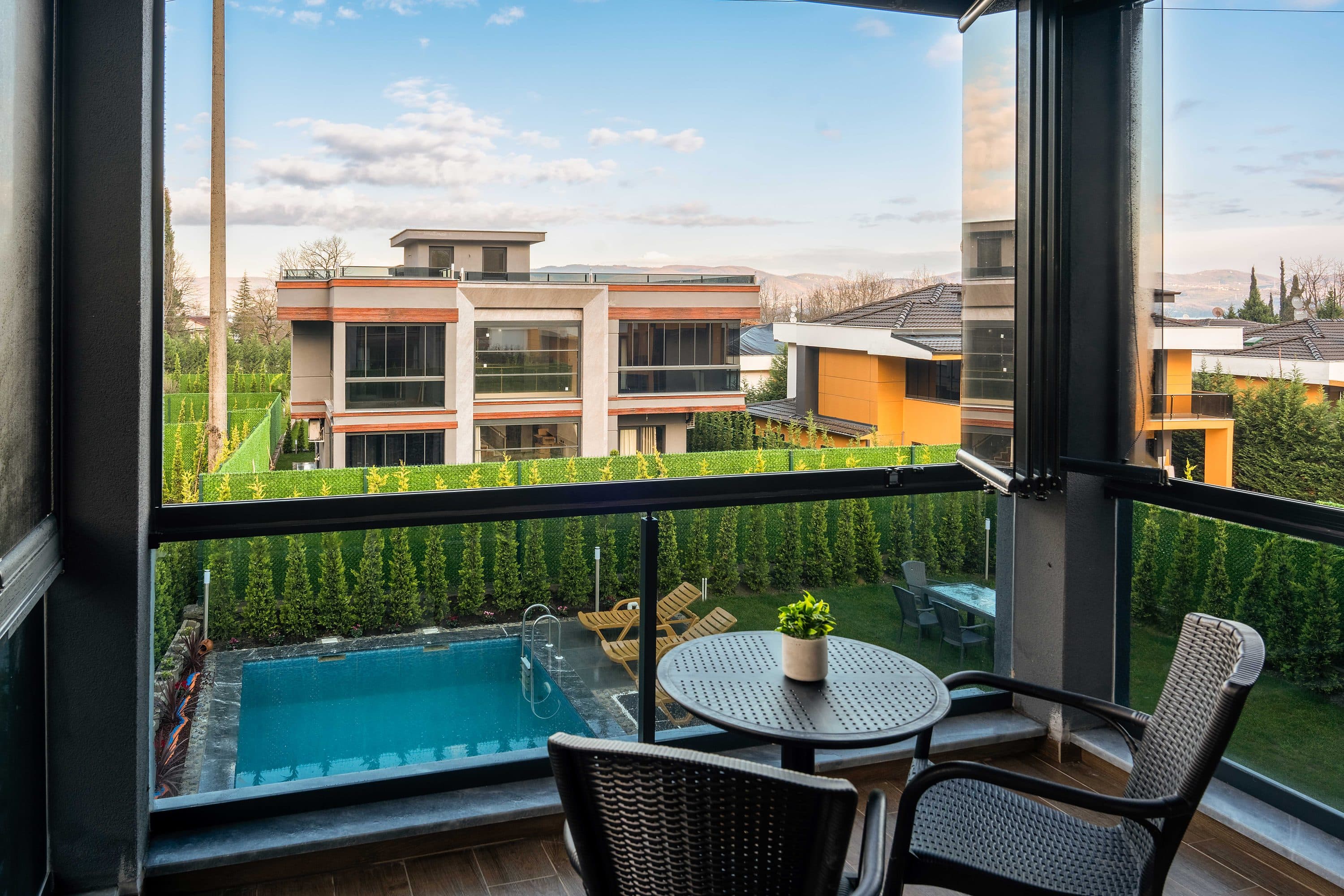 Terrassentisch und Stühle über dem Pool, mit Blick über die Nachbardächer.