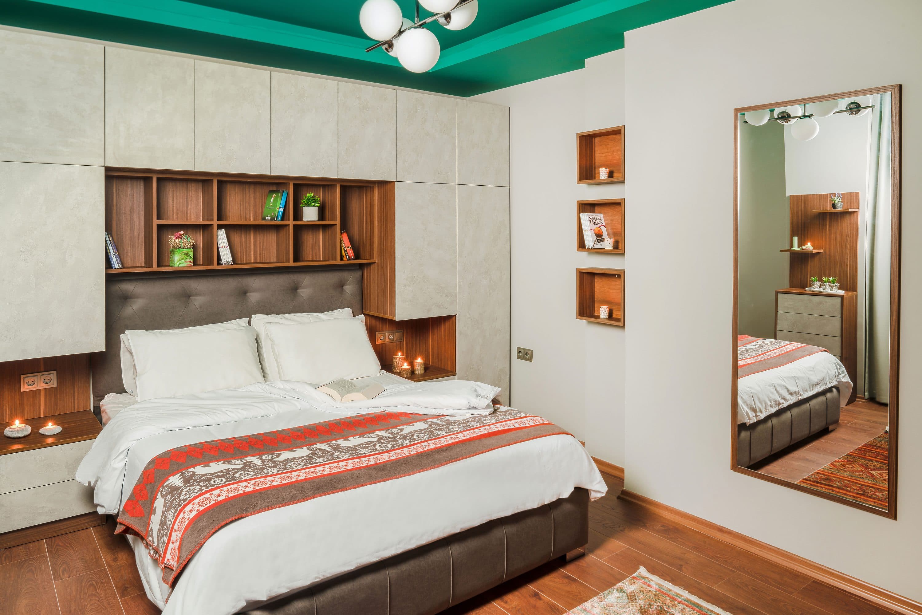 Schlafzimmer mit eingebautem Holzregal über dem Bett und einem verspiegelten Ankleideelement.