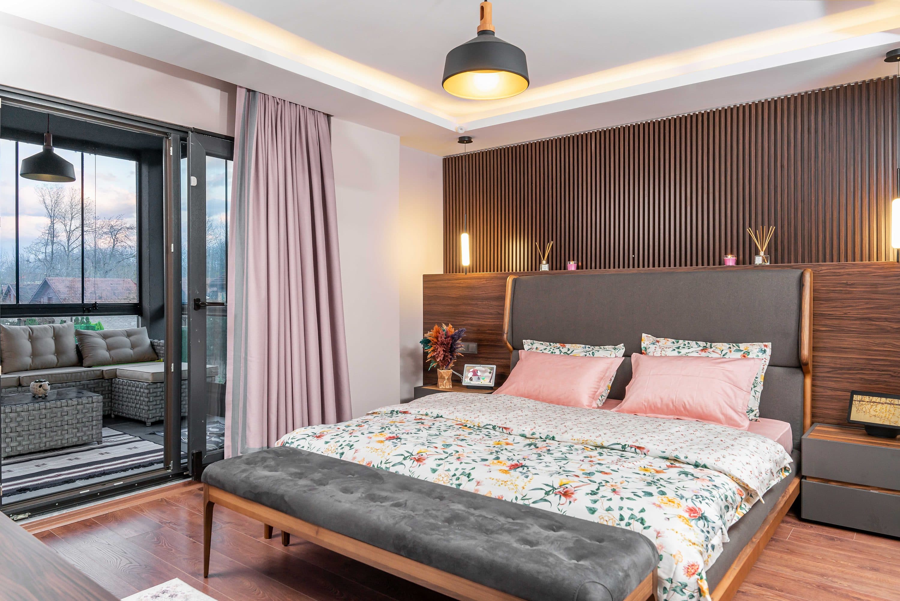 Schlafzimmer mit einer Lamellen-Kopfteilwand aus Nussbaum über die ganze Zimmerbreite.